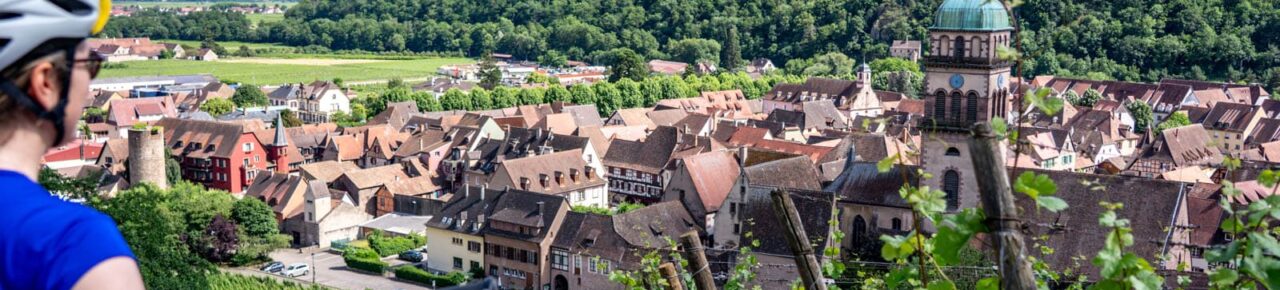 Ciclista mirando el pueblo de Kaysersberg en Alsacia